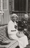 Två kvinnor på en soffa utanför Pettersbergs gård, 1930-tal