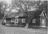 Spjälla gård, Hagryd i Släp. En trädgårdsmöbel står mellan trädet och den lilla utbyggnaden.