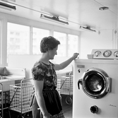 Kvinna vid tvättmaskin i tvättstuga i Markbacken, 1960-tal