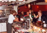 Robert Säll serverar gäster i baren på Moulin Rouge, restaurang och diskotek med adress Kvarnbygatan 1 i Mölndal, år 1988.