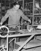 Förrådsarbetare monterar något på elverket, 1960-tal