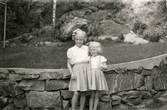 Första examensdagen för Eva i juni 1952. Systrarna Eva (gift Kempe) Pettersson och Karin (gift Hansson) står framför stenmuren på Gamlehagsvägen i Torrekulla.