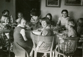 Barn sitter samlade runt ett bord då det är födelsedagskalas för Eva Pettersson (gift Kempe) som fyller 10 år, Gamlehagsvägen i Torrekulla, påskdagen 16/4 1954.
Relaterat motiv: 2023_0146.