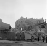 Byggarbetare står under grävmaskinens skopa under rivning av Fredsgatan 8, 10, mars 1973