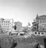 Grävmaskinen hämtar rivningsmassa för att fylla lastbilen vid rivning på Fredsgatan, 1970-tal