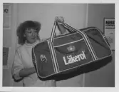 Tävling i Inside oktober 19 87, Gissa året. Elisabeth Sundström visar upp priser att vinna.
På denna bild visar hon en stor västa med texten 