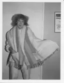 Tävling i Inside oktober 19 87, Gissa året. Elisabeth Sundström visar upp priser att vinna.
På denna bild visar hon en stor randig filt med 2 fickor på att ha som sjal.