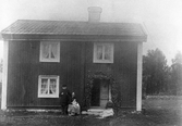 Familj framför hus i Knista, 1910-tal