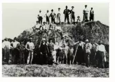 Skördearbete. Höslåtter på Lindhofs kungsgård 1925. Ett stort antal män och pojkar har ställt upp sig för fotografen både nedanför, i och ovanpå den stora höstacken.