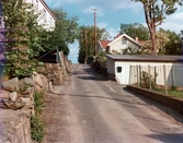 Åldermansgatan i Mölndals Kvarnby, omkring 1975-1980. På höger sida av gatan ses husen Roten K 15 och 14 samt uthuset till Roten K 13.