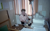 Kvinna i telefon vid skrivbord i Tysslinge, 1990