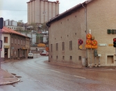 Kvarnbygatan i Mölndals Kvarnby, omkring 1975-1980. Vy från Gamla torget. Byggnaden till vänster är Kvarnbygatan 45. Den till höger är Kvarnbygatan 6 tillhörande SOAB. I bakgrunden SOABs silobyggnad.