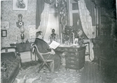 Kolbäck sn.
Interiör med man sittande vid skrivbord, c:a 1900.