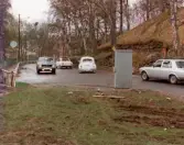 Trafik på Pixbovägen i Grevedämmet, Mölndal, omkring 1975-1980. Genom träden skymtas Grevedämmets skola.