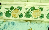 Detaljbild av målad taklist, dekorerad med gula rosor och gröna blad.