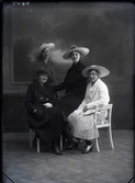 Ateljéfoto med fyra unga kvinnor i ytterkläder och bredbrättade hattar. Beställare och sannolikt avbildad: Fröken Wiborg, Falkenberg.
