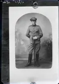 Reprofotografi av ett ateljéfoto med en man i uniform med trekantig hatt. Han håller en värja framför sig. Beställare: Oskar Pehrsson, Måsalyckan, Falkenberg.