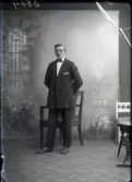 Ateljébild. Ung man stående i helfigur iklädd kavaj och fluga. Beställare: Hjalmar Bengtsson. (Adr. Rol. Danielsson, Falkenberg)