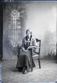 Ateljébild. Kvinnoporträtt, ung kvinna sittande i helfigur. Beställare: Elsa Backvall, Västra Gärdet 31, Falkenberg