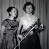 Bild tagen i samband med att flyktingar ifrån Ungern kom 1956.  Två kvinnor som står på scen. Den ena kvinnan håller i ett stråkinstrument i Godtemplargården hösten 56 - våren 57.