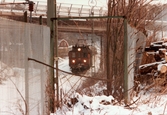 Ett tåg passerar under en bro i Grevedämmet, Mölndal, i januari 1984.