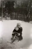 Vinter i Lackarebäck, Mölndal, på 1950-talet. Jan Erik Wäne sitter på sin kälke i snön.