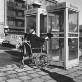 Rullstolsbunden kvinna vid telefonkiosk, 1960-tal