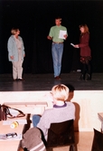 Tre personer står på scenen och repeterar i Teaterhuset, okänt årtal. En person sitter nedanför scenen och tittar på.