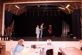 Tre personer står på scenen och repeterar i Teaterhuset, okänt årtal. Två personer sitter nedanför scenen och tittar på.