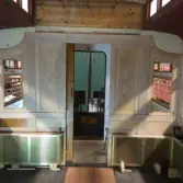 Vägg mellan kafédelen och vestibulen i SJ Ro2 2702.