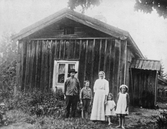 Familj vid husgavel, ca 1900
