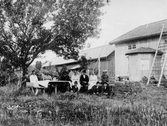 Kvinnor och män runt trädgårdsbord, 1910-tal