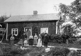 Familj framför stuga, 1890-tal
