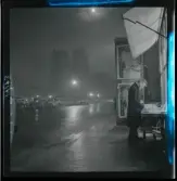 1950. Paris. Man på gata med Notre Dame i bakrunden, kväll