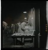 1950. Paris. Två män utanför ett antikvariat, kväll