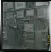1950. Paris. En man stå inne i en butik med konst.