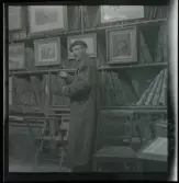 1950. Paris. En man stå inne i en butik med konst.