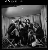 505 Wityansky Teaterskola för Allers. En grupp teaterelever på scen. Alla samlas för att betrakta en teckning som en unga man sittandes i mitten av gruppen visar upp.