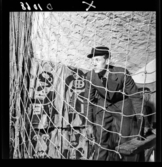 511 Gripsholms Slott för Allers. En man står och hukar i ett valv. Ett nät är uppspänt, målade textilier på väggen.