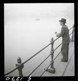 542 Dimma. En man står och blickar ut över vattnet i dimma.