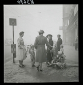 542/B Dimma. Några kvinnor med barn och barnvagnar har stannat för att prata på trottoaren.