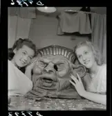 561 Operan för Allers. Två kvinnor lutar sig emot en teatermask.