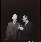 561 A Operareportage för tidningen Vi. Två män i kostym samtalar. Den ene visar båda tummar upp.