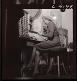 561 A Operareportage för tidningen Vi. Kvinna sitter på sin arbetsplats i biljettkassan.