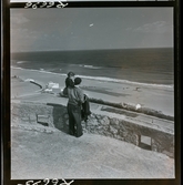 568 F. Stieg Trenter, Torremolinos. En man bärandes på en liten flicka står högt och blickar ut över stranden och havet.