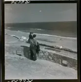 568 F. Stieg Trenter, Torremolinos. En man bärandes på en liten flicka står högt och blickar ut över stranden och havet.
