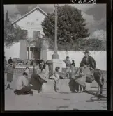 568 F. Stieg Trenter, Torremolinos. Stieg Trenter får sina skor putsade vid en springbrunn på ett torg. Han samtalar med en man som sitter upp på en åsna.