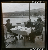 568 F. Stieg Trenter, Torremolinos. Stieg Trenter och två kvinnor sittter och skålar vid ett bord intill en pool.