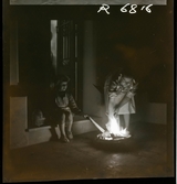 568 F. Stieg Trenter, Torremolinos. En flicka och en kvinna på tröskeln utanför ett hus. De bränner något på ett fat framför dem.