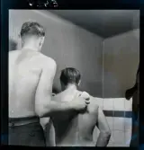 577 Skrubba mig på ryggen Omslag SE. En man tvättar en annan på ryggen.